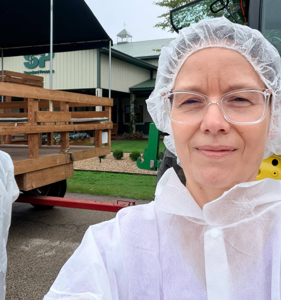 Debi McKee wearing white hair net and white coat in front of Standard Process.